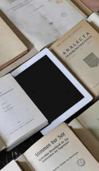 Symbolic image: A tablet lies among printed issues of academic journals